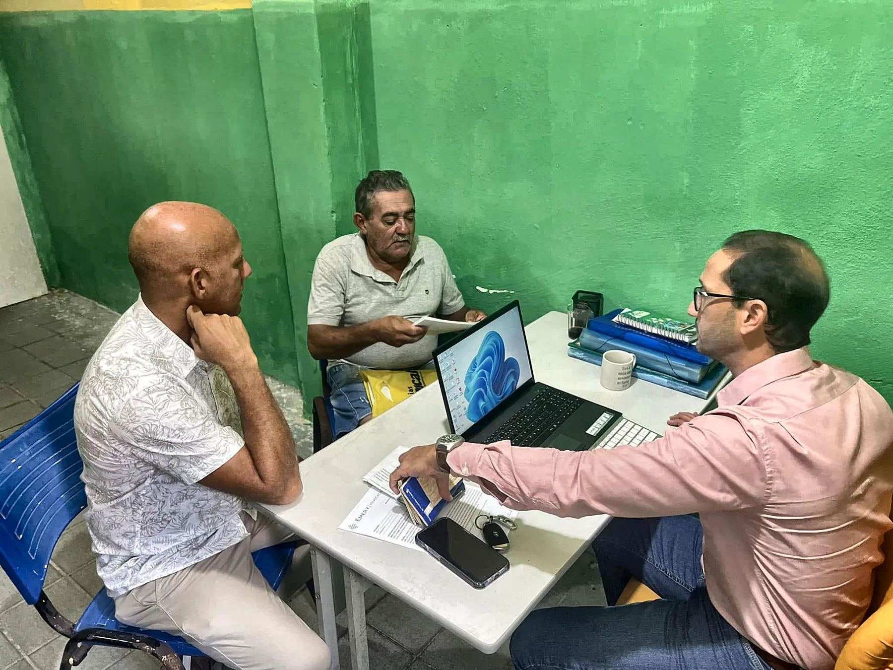 Advogado orientando dois atendidos em atendimento previdenciário